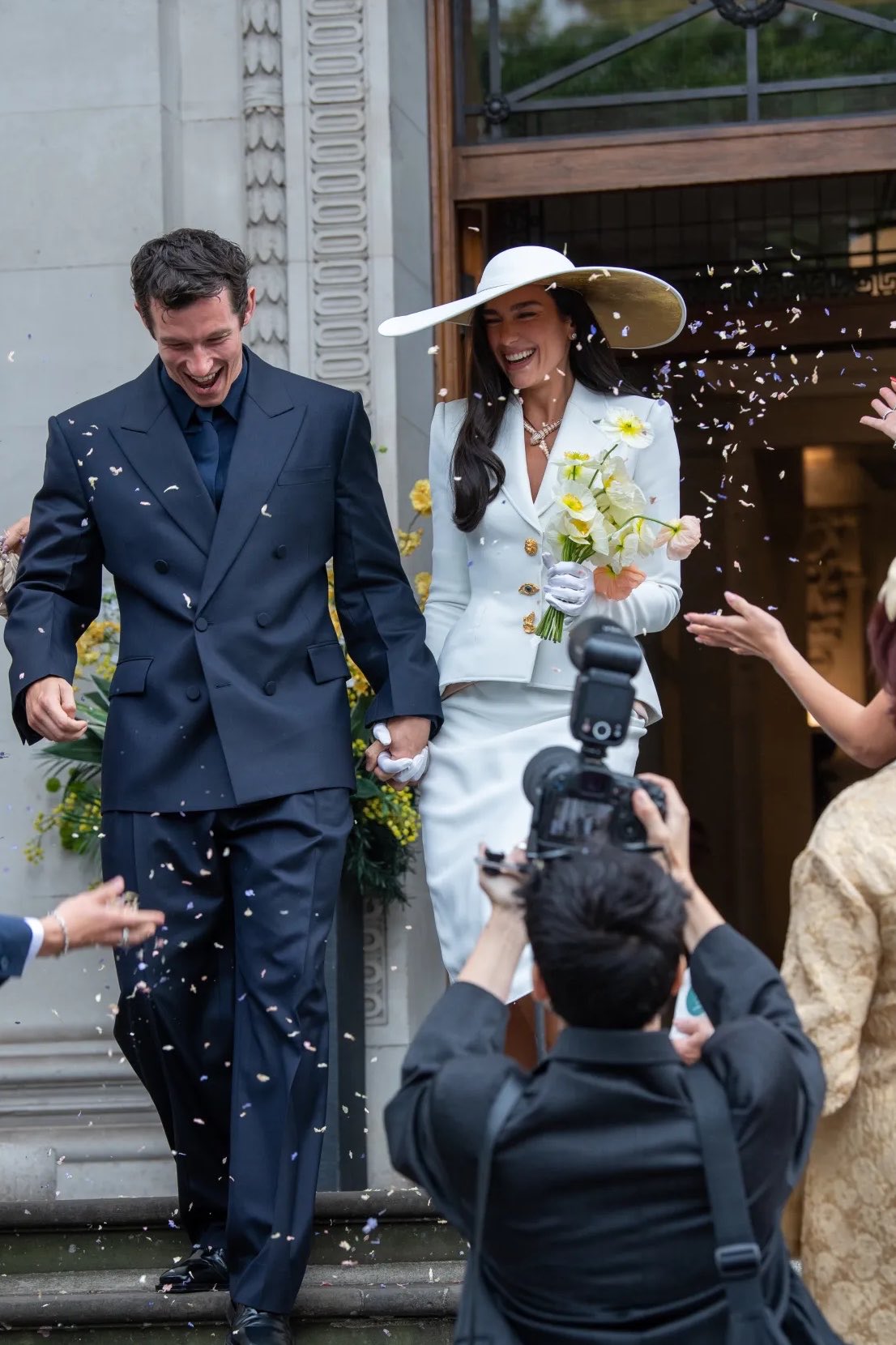 Callum Turner laughs through confetti outside the registry